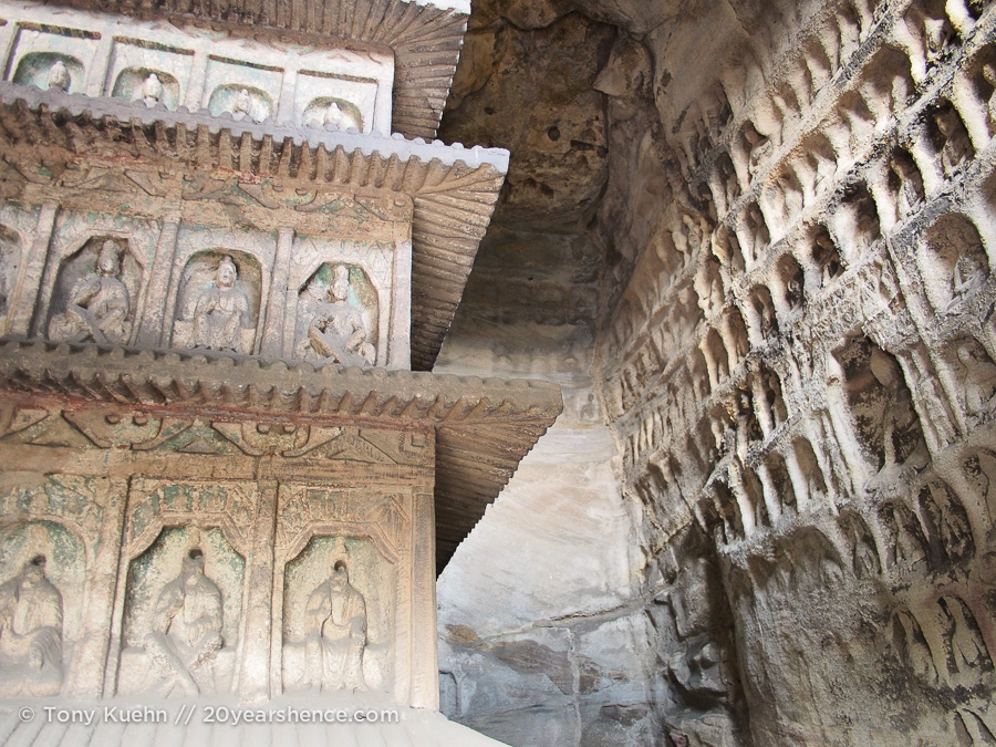 A cave interior. the walls are covered with carvings and the central pillar is part of the cave itself, carved out of solid rock